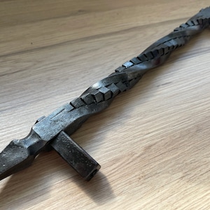 May include: A black metal door handle with a twisted design. The handle is approximately 25 cm long and has a square base.