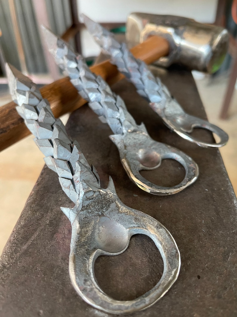 May include: Three silver bottle openers with a textured, twisted design. The bottle openers are made of metal and have a loop at the top for hanging.