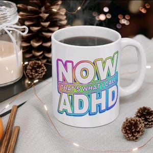 May include: White ceramic coffee mug with a rainbow design that says "NOW THAT'S WHAT I CALL ADHD".