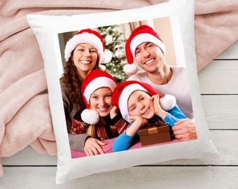 May include: A family of four wearing Santa hats poses for a Christmas photo. The family is sitting in front of a decorated Christmas tree.