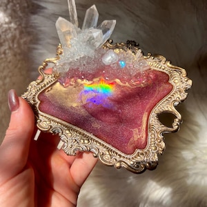 May include: Ornate, gold-toned tray with a burgundy and gold interior, topped with clear quartz crystals. The tray's surface reflects a rainbow of colors. The tray has a decorative, vintage-inspired design.