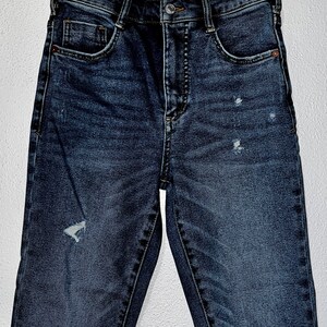 May include: Dark blue denim jeans with distressed details and a high waist.