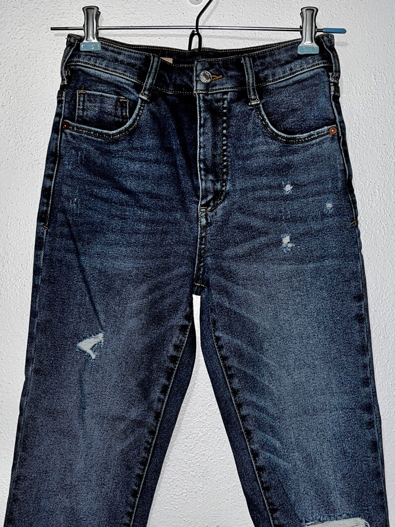 May include: Dark blue denim jeans with distressed details and a high waist.