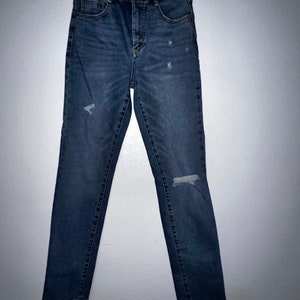 May include: A pair of dark blue denim jeans with distressed details and a frayed hem.