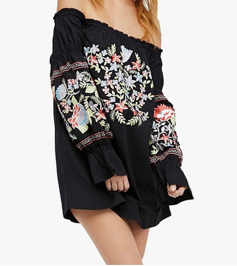 May include: A black off-the-shoulder dress with long sleeves and a floral embroidery design. The dress has a loose fit and a slightly flared skirt.