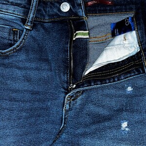 May include: A pair of blue denim jeans with a zipper fly and a small pocket on the front. The jeans have a distressed look with some fading and holes.