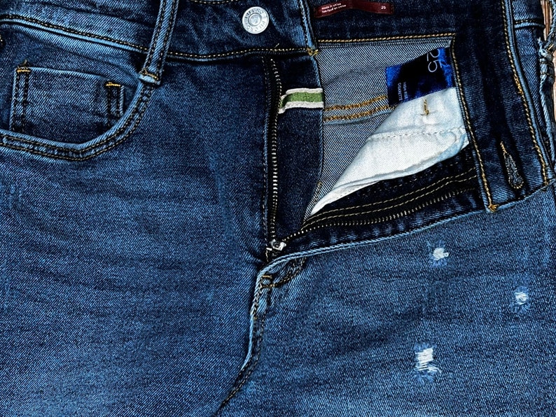 May include: A pair of blue denim jeans with a zipper fly and a small pocket on the front. The jeans have a distressed look with some fading and holes.