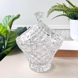 Könnte beinhalten: Eine klare Glasschüssel mit Diamantenmuster und Deckel. Die Schüssel hat einen breiten Boden und einen schmalen oberen Rand.