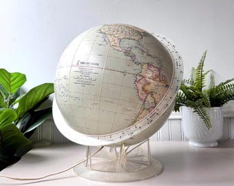 May include: A vintage Time-Life globe with a light-colored map, mounted on a clear plastic stand. The globe features a white meridian ring and a power cord. The text "TIME-LIFE GLOBE" is visible on the globe.