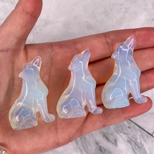 Könnte beinhalten: Drei regenbogenfarbene Opal-Wolf-Figuren. Die Wölfe sind in sitzender Position mit nach oben geneigtem Kopf geschnitzt.