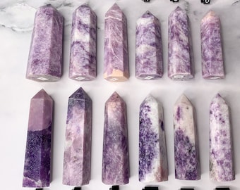May include: Twelve purple and white amethyst crystal points arranged in two rows of six. Each point is labeled with a number from 1 to 12.