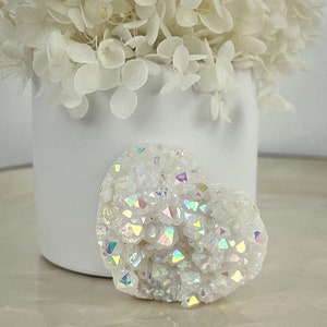 May include: A white heart-shaped crystal with iridescent rainbow sparkles. The crystal is made of many small, faceted pieces.