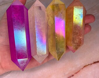 May include: Four iridescent crystal points in shades of purple, clear, and yellow. The points are faceted and have a smooth, polished finish.