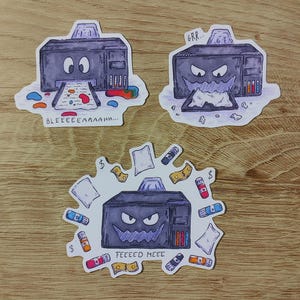 May include: Three stickers depicting cartoon printers with emotive faces. One sticker shows a printer with the text "BLEEEEEAAAAHH...". Another sticker shows a printer with the text "GRR...". The third sticker shows a printer with the text "FEEEED MEEE".