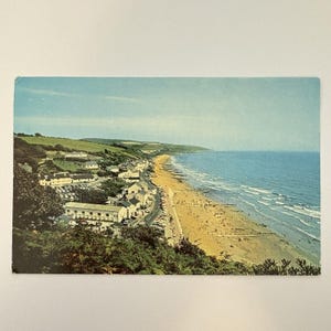 Puede incluir: Una taza de cerámica blanca con un asa negra y el texto "But First, Coffee" en negro, con una fuente de estilo manuscrito. La taza está sobre una superficie blanca.