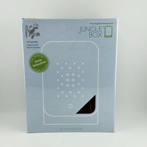 May include: A light blue rectangular box for the Jungle Box sound device. The front features the text The Original Relaxound JUNGLE BOX, a graphic of a toucan, and a green circular badge stating Feel Malaysian Deep Relaxation Jungle Serenity.