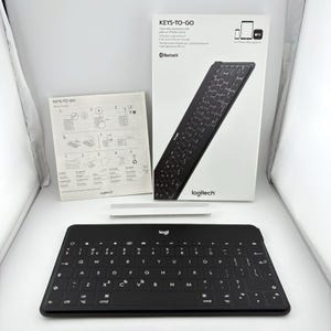 May include: A black Logitech Keys-To-Go ultra-slim Bluetooth keyboard with a white product box featuring the text KEYS-TO-GO and a setup guide with illustrated instructions. The keyboard has a standard QWERTY layout with white lettering.