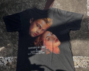 May include: Black t-shirt featuring Leonardo DiCaprio and Kate Winslet from the movie Titanic. The graphic includes their faces and the text "LEONARDO DICAPRIO & KATE WINSLET Special Photographs from TITANIC."