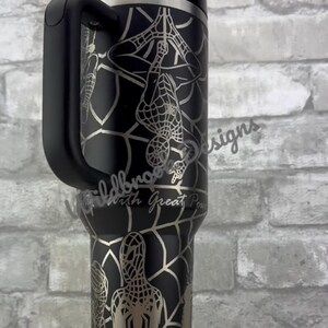 Puede incluir: Vaso negro con asa, con un dise&ntilde;o plateado de Spider-Man. El dise&ntilde;o incluye un patr&oacute;n de telara&ntilde;a y al superh&eacute;roe en varias poses. El vaso tiene un asa negra y una tapa transparente con pajita.