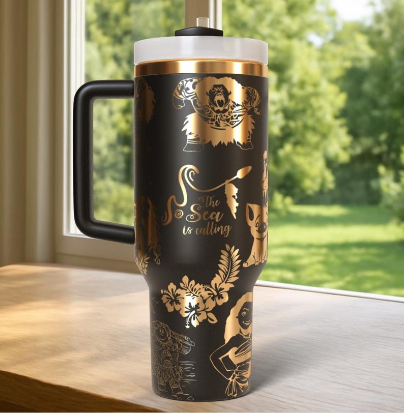May include: Black travel mug with gold-colored illustrations of characters and floral designs. The mug has a black handle, a white lid, and the text "The Sea is Calling".