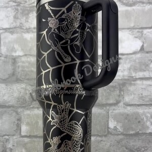 Puede incluir: Vaso de acero inoxidable negro con un dise&ntilde;o plateado de Spider-Man. El vaso tiene un asa, una tapa y una pajita. El dise&ntilde;o incluye a Spider-Man y el texto "With Great Responsibility".