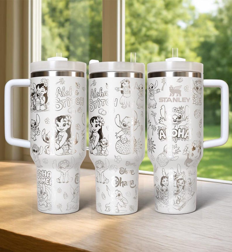 May include: Three white insulated tumblers with silver lids and handles. Each tumbler features a different design of the character Stitch from the Disney movie Lilo & Stitch, with the words "Aloha" and "Ohana" in a silver colour.