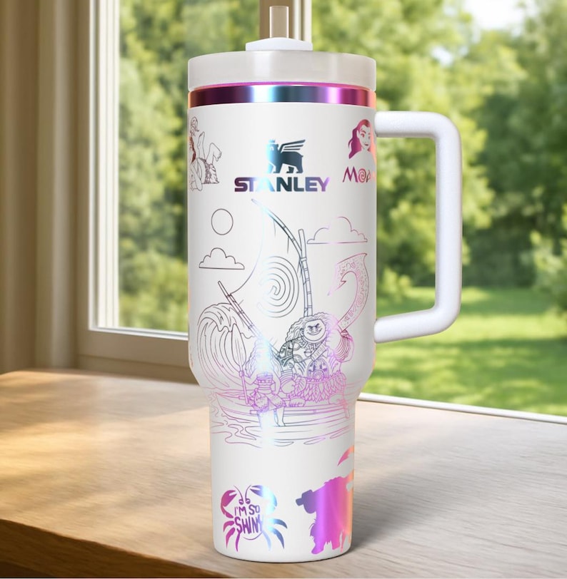 May include: White Stanley tumbler with a handle, featuring a colorful design with characters and imagery from a popular animated film. The tumbler has a white lid and a handle. The design includes the Stanley logo and the words "I'm so shiny".