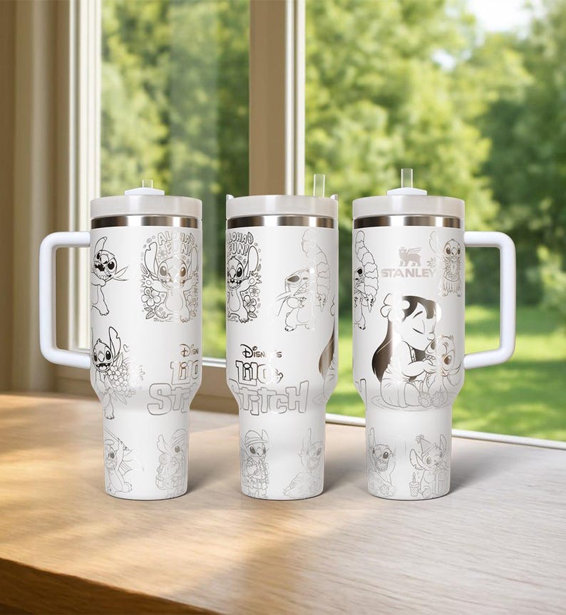 May include: Three white Stanley tumblers with silver-colored illustrations of Stitch from Disney's Lilo & Stitch. Each tumbler has a white handle, lid, and straw. The text "Disney Lilo & Stitch" is visible on the tumblers.