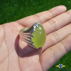 May include: A silver ring with a large, oval-shaped, light green gemstone.