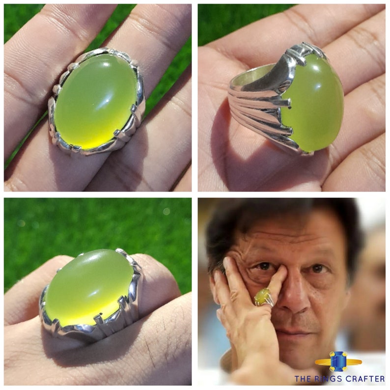 May include: A silver ring with a large, oval-shaped, light green gemstone. The ring has a detailed, ornate design.