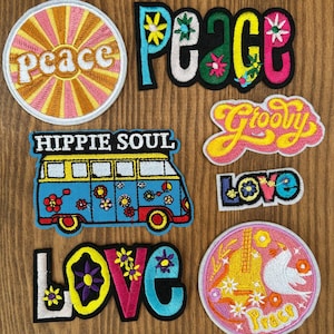 May include: A collection of embroidered patches with a retro, hippie theme. Designs include the words "Peace," "Groovy," and "Love," along with a peace sign, a guitar, and a flower-covered van. The patches feature bright colors and floral accents.
