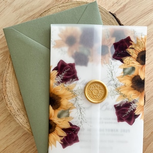 Puede incluir: Conjunto de invitación de boda con girasoles y rosas burdeos. La invitación está sellada con un sello de cera dorado e incluye un sobre verde salvia. El diseño está impreso en papel translúcido.