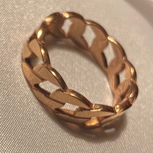 Puede incluir: Un anillo de tono dorado con un diseño grueso y robusto. El anillo está hecho de formas ovaladas entrelazadas.