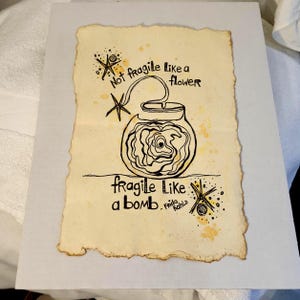 Puede incluir: Obra de arte dibujada a mano sobre papel envejecido. La imagen presenta un dibujo lineal negro de un tarro con una rosa en su interior, y el texto "Not fragile like a flower, fragile like a bomb. Frida Kahlo."