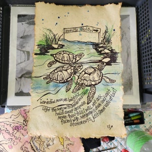Op de afbeelding: Een rechthoekig vel gestructureerd, cr&egrave;mekleurig papier met een zwarte inktillustratie van drie zeeschildpadden die in blauw en groen aquarelwater zwemmen. Een bordje toont Terrapin Station. De tekst bevat Inspiration move me brightly.