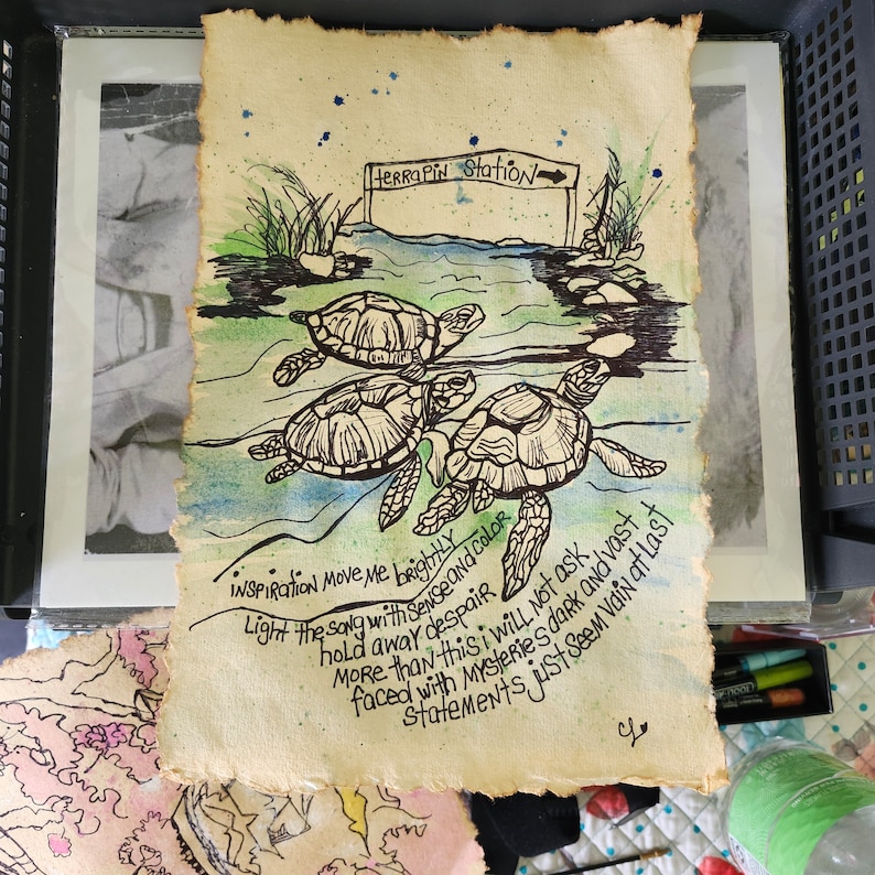 Op de afbeelding: Een rechthoekig vel gestructureerd, cr&egrave;mekleurig papier met een zwarte inktillustratie van drie zeeschildpadden die in blauw en groen aquarelwater zwemmen. Een bordje toont Terrapin Station. De tekst bevat Inspiration move me brightly.