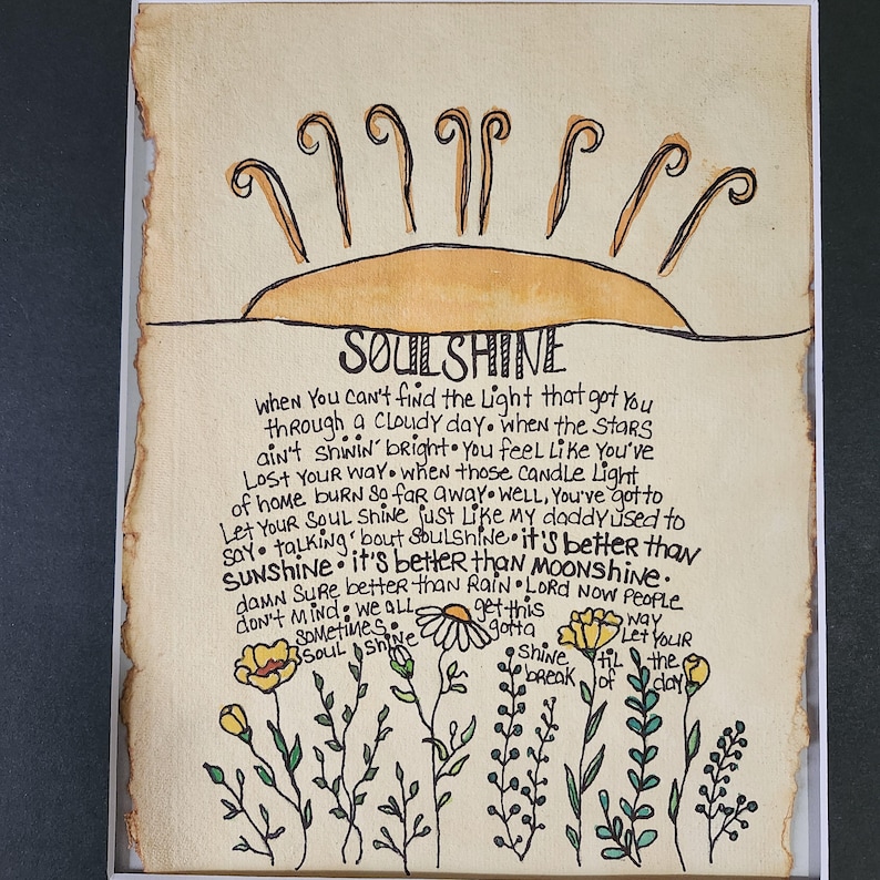 Pu&ograve; includere: Un'illustrazione disegnata a mano di un sole con raggi e le parole "SOULSHINE" in un font scritto a mano. Il testo sotto il sole recita: "Quando non riesci a trovare la luce che ti ha portato attraverso una giornata nuvolosa. Quando le stelle non brillano, ti senti come se ti fossi perso. Quando quelle luci di candela di casa bruciano cos&igrave; lontano. Beh, devi lasciare che la tua anima brilli come faceva mio padre. Parlando di SOULSHINE. &Egrave; meglio di SUNSHINE. &Egrave; meglio di MOONSHINE. Certo che &egrave; meglio della pioggia. Signore, ora la gente non se ne preoccupa. Abbiamo tutti questa strada. A volte, l'anima brilla. Brilla, devi rompere fino al giorno. Lascia che tu riempia il giorno."