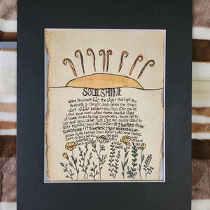 Pu&ograve; includere: Un'illustrazione disegnata a mano di un sole con le parole "SOULSHINE" scritte in nero. Il testo sotto il sole dice "when you can't find the light that got you through a cloudy day. when the stars ain't shinin' bright you feel like you've lost your way when those candle light of home burn so far away well, you've got to say talking 'bout soulshine - it's better than sunshine - it's better than moonshine. dawn sure better than rain lord now people don't mind we all gotta let your shine til the break of day"