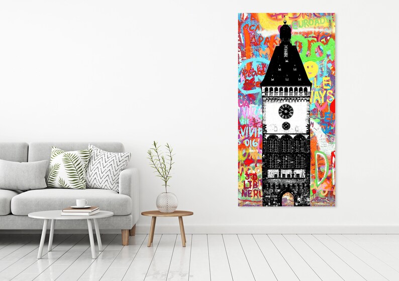 Puede incluir: Una ilustraci&oacute;n en blanco y negro de una torre del reloj con una esfera del reloj y un techo puntiagudo. La torre est&aacute; sobre un fondo colorido de grafitis con palabras y frases en diferentes idiomas.