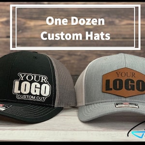 May include: Two custom trucker hats with the text "Your Logo" on them. One hat is black with a gray mesh back and the other is gray with a white mesh back. The text on the black hat is white and the text on the gray hat is on a brown leather patch.