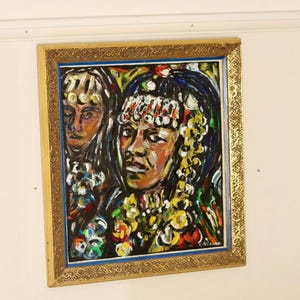 Puede incluir: Una pintura al óleo en un marco dorado representa a dos mujeres con cabello y piel oscuros. La figura central lleva un tocado enjoyado y detalles florales coloridos. La obra utiliza una paleta vibrante de rojos, amarillos, azules y verdes.