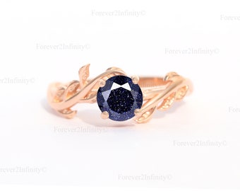 Könnte beinhalten: Ein Ring aus Roségold mit einem blauen Edelstein, der in einem Blattdesign gefasst ist.