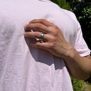 May include: A silver band ring with a flat, wide surface.