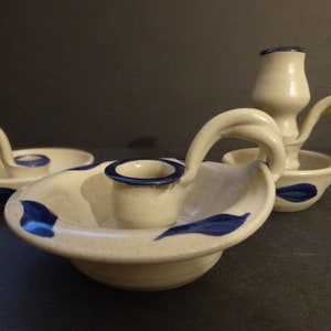 May include: Three ceramic candle holders with blue and white designs. The holders have a handle and a small bowl for the candle.