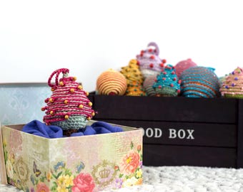 Pode incluir: Uma caixa de madeira com o texto "Wood Box" na frente, cheia de enfeites de crochê coloridos. A caixa está aberta e um enfeite de crochê rosa e verde está sentado em cima da caixa.