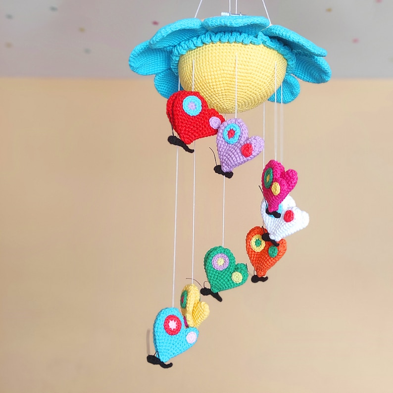 May include: A colourful crocheted baby mobile with a blue and yellow sun and hanging butterflies in various colours, including red, pink, green and purple.