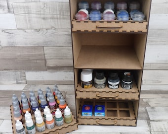 May include: A wooden paint storage organizer with multiple shelves and drawers. The organizer is filled with various bottles of paint, including acrylic, metal, and wash paints. The organizer is a great way to keep your paints organized and easy to find.