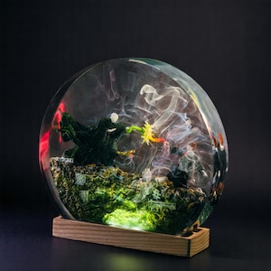 May include: A clear resin sphere with a dark green and black figure casting a spell, surrounded by swirling white smoke. The sphere is lit from below with a green light and sits on a wooden base.