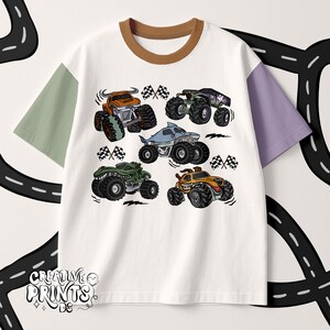 May include: White t-shirt with a brown collar and color-blocked sleeves in green and purple. The shirt features a graphic of six cartoon monster trucks in various colors, with checkered flags.