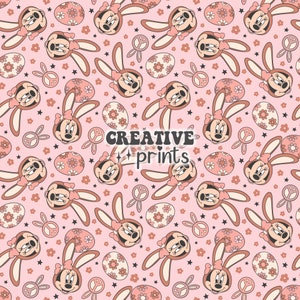Op de afbeelding: Een naadloos roze en bruin patroon met een cartoonfiguur met konijnenoren, vredestekens, bloemen en paaseieren. De tekst "CREATIVE prints" staat in het midden van het patroon.